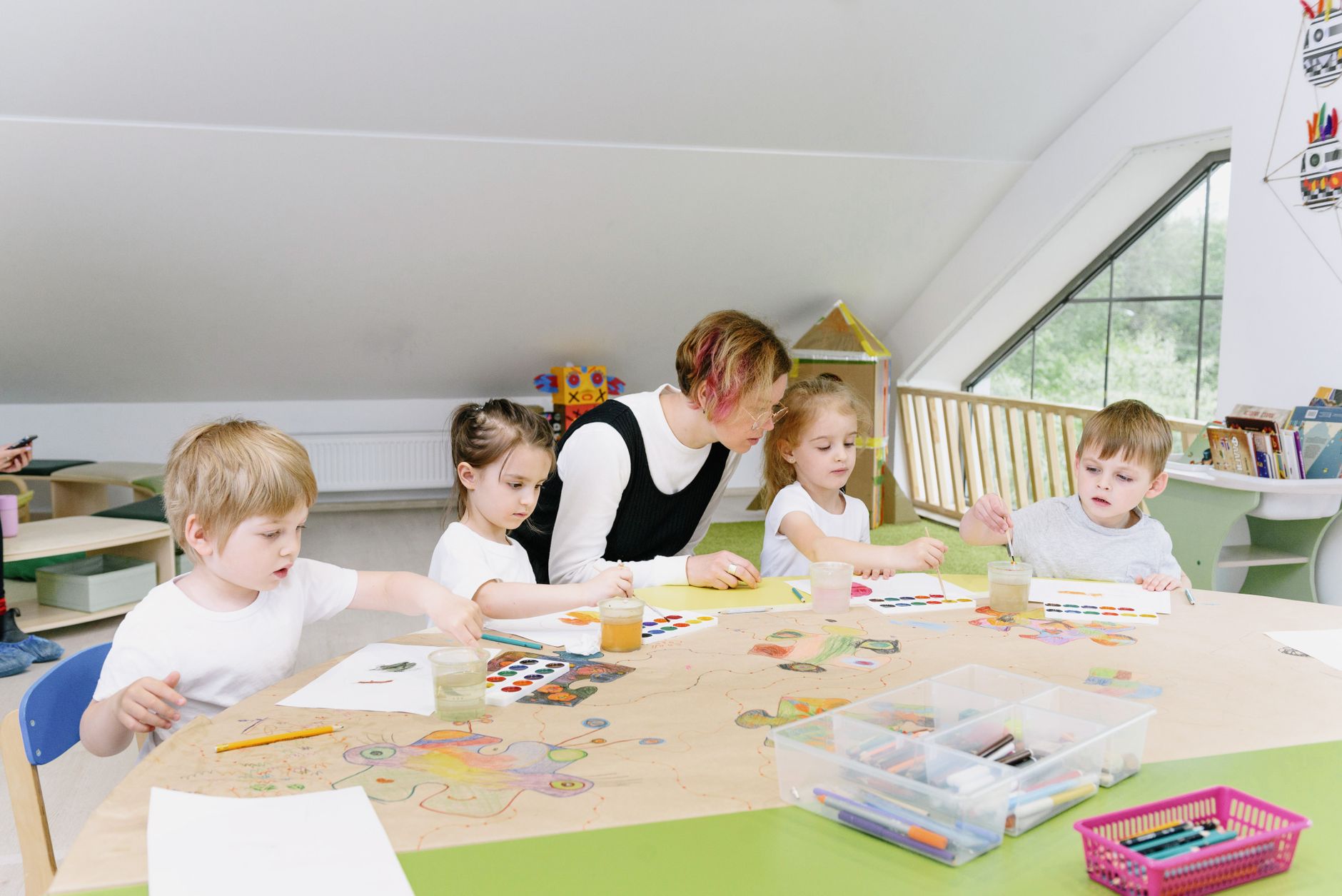 A teacher and children crafting together at a classroom table